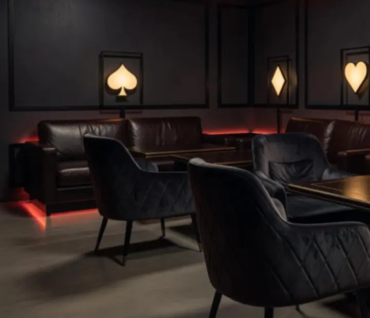 Sötét lounge részleg puha székekkel, barna bőrkanapékkal és hangulatos fényekkel.